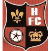 A shield-shaped emblem with four quadrants displaying a fleur-de-lis, soccer ball, crown, and 'H FC' text in red, black, white, and gold colors.