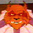 A pixelated orange-red creature with glowing yellow eyes, bared teeth, and pinkish ears against a dark background.