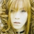 Static pixelated image of a person with long blonde hair and light skin tone, framed by vertical golden elements on both sides against a blurred background.