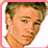 Pixelated image of a person with light brown hair and blue eyes, wearing a white shirt against a pink border background.