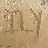 Pixelated static image with beige and brown tones showing indistinct shapes resembling stylized letters or symbols on a textured background.