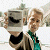 A pixelated image split into two sections: a person holding an object on the left and green text reading 'Original Icons .com' on the right.