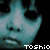 Pixelated face with teal and black tones, large dark eye sockets, small nose dots, mouth in a grimace, white text 'TOSHiO' at bottom right.