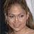 A pixelated close-up of a person with light brown hair, fair skin, and a neutral expression, cropped to show shoulders and upper chest against a dark background.