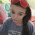 Pixelated image of a person with long dark hair wearing a red beret and gray top against colorful blurred background.