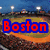 A baseball stadium at night with a crowd, featuring red text overlays on blue backgrounds in the top-left and top-right