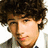 Pixelated portrait of a person with curly brown hair and light skin, set against a black background with red text elements.
