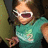 Pixelated image of a person in teal shirt with white sunglasses and open mouth, next to green object, on split background.