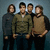 Four pixelated figures stand side-by-side against a gradient background, wearing casual clothing in muted tones.