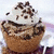 A cupcake with light brown cake, white frosting, and chocolate sprinkles on top, shown in a of four views with one view missing