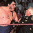 Pixelated image of a person in light-colored clothing holding an object against a dark background with blue and pink tones.