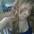 Pixelated static image of a person with light hair and a white top, partially obscured by low resolution, with a blue and gray background.