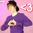 A person in a purple sweater and dark cap forms a heart shape with hands against a pink background, next to a '<3' symbol that changes color across six