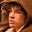Pixelated image of a person in brown hooded clothing with curly hair, next to text elements on white background.