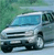 Pixelated image of a light blue vehicle with dark blue accents, positioned at an angle against a green and blue background.