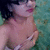 Pixelated static image of a person with dark hair and light skin, wearing pink lipstick against a teal background.