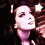 Pixelated image of a person with long dark hair, closed eyes, and pinkish skin tones against a dark background.
