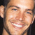 Static close-up of a smiling person with light skin, brown eyebrows, and visible teeth in a pixelated 50x50 icon format.