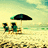 Beach scene with two green chairs under a black umbrella on sandy shore, ocean and sky in background.