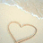 A pixelated heart shape drawn in light brown on a beige background with faint blue and white wave-like patterns at the top.