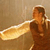 Static pixelated image of a figure with brown hair holding a large golden object against a beige background.