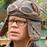 Static 48x48 pixel buddy icon showing a person with long hair wearing a gray cap, set against a blurred greenish background.