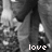 Black-and-white pixelated image of two figures in dark clothing with a light-colored object, featuring the word 'love' at bottom right.