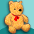 Pixelated static image of a yellow teddy bear with one black eye and one brown eye, wearing a red bow tie against a teal background.