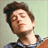 Pixelated image of a person with brown hair wearing a blue and white striped shirt against a light green background, next to bold black text on red.