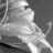 Pixelated grayscale image of a figure in a cap and jacket holding a long object, set against a dark background with visible pixelation and low resolution.