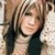 Pixelated static image of a person with light brown hair and dark clothing against a blurred background.