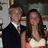 Two people in formal attire stand side-by-side; the right person's hand moves from a neutral position to forming a heart shape while text appears over them.
