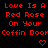 Red pixelated text on black background reads 'Love Is A Red Rose On Your Coffin Door' with two red heart symbols below the text.