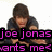 Pixelated image of a person with brown hair wearing dark clothing, overlaid with bold pink text reading "joe jonas wants me" on black bars.