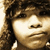 A sepia-toned portrait of a person with curly hair, displayed in a with visible pixelation