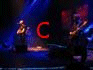 Animated sequence of a band performing on stage with changing red text overlays spelling 'Coldplay' across frames.