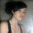 Pixelated image of a person with short black hair wearing a dark sleeveless top, facing right with a slight smile.