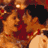Pixelated static image of a stylized figure with orange and red tones, featuring dark hair or headwear against warm background hues.