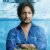 Pixelated image of a person in a blue shirt with arms crossed against a light blue background.