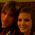 Two pixelated faces in warm orange and brown tones, side-by-side, with visible smiles and dark hair against a dark background.