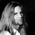 A grayscale pixelated image of a person with long hair, viewed in profile against a dark background, showing a neutral expression.