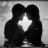 Two dark silhouetted figures in close embrace with a bright white cross symbol between them on a gray pixelated background.