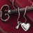 A silver key with a heart-shaped pendant hangs from a red fabric background, accompanied by orange pixelated text on black.