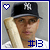 A baseball player wearing a black cap with white NY logo holds a light brown bat across his chest, with blue text #13 below and a heart icon in the top left corner.