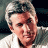A pixelated image of a person with short light-colored hair wearing a white shirt, next to green text reading 'OriginalIcons.com' on a dark background.