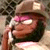 Pixelated static image of a cartoon character with dark hair, pink eyeshadow, and a brown hat holding an object near their face.