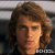 Pixelated close-up of a person with light brown curly hair, neutral expression, and visible ear, against a blurred background with horizontal light and dark bands.
