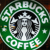 Green circular logo with white text 'STARBUCKS' top and 'COFFEE' bottom, featuring a black-and-white siren with crown and stars.