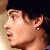 Pixelated close-up of a person's face in profile, wearing a dark cap and small earring, with light skin tone and visible earlobe.