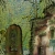 Pixelated static image shows two figures in a green-toned outdoor scene with blurred foliage background.